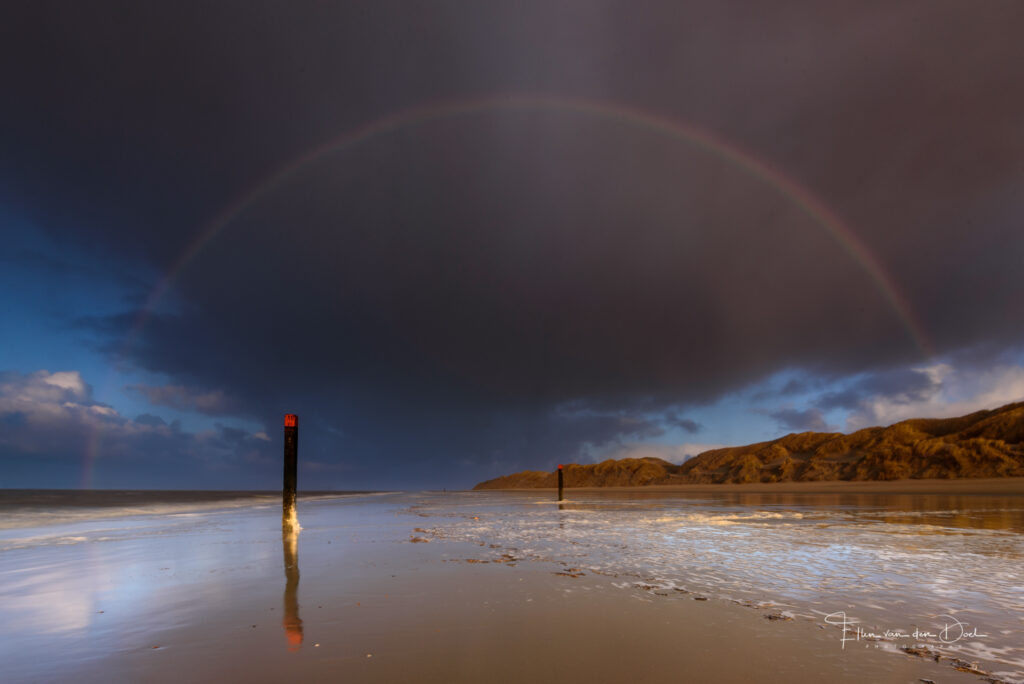 Een regenboog boven het strand